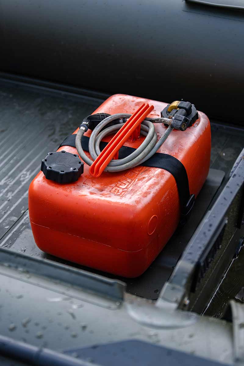 Orange fuel tank secured on an inflatable boat, essential for boating and fishing adventures.
